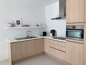 Eine moderne Küche mit Spüle, Herd und Holzschränken.
