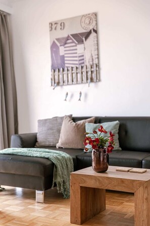 Ein Wohnzimmer mit einer Couch, einem Couchtisch und einem an der Wand hängenden Kunstwerk.