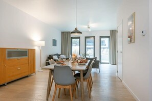 A dining area with a table set for four, a sofa, and a wooden cabinet.