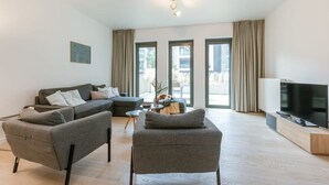 Ein modernes Wohnzimmer mit einer Sofagarnitur, einem Couchtisch und einem Fernseher.
