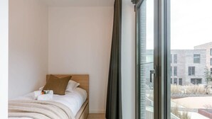 Ein Schlafzimmer mit einem Bett, einem Fenster und Blick auf Gebäude.