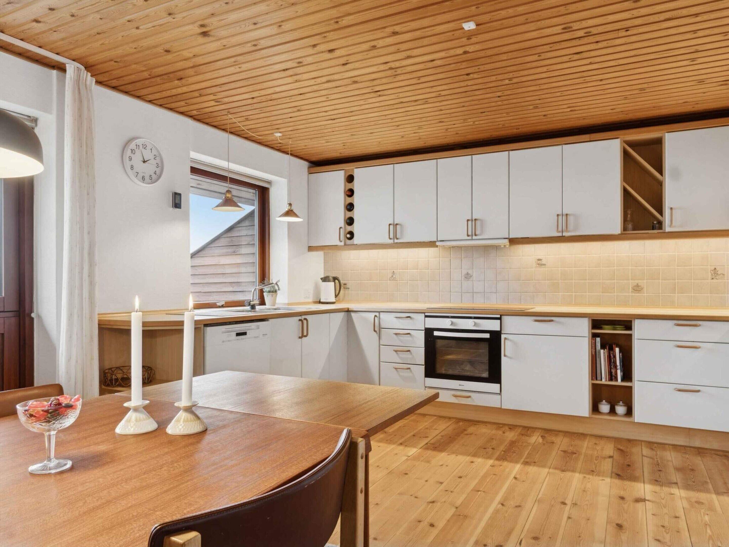 Eine moderne Küche mit Holzausstattung, einem Einbauofen und einem Essbereich mit Holztisch und Stühlen.