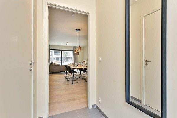 View from the entryway into a modern dining and living area with natural light.