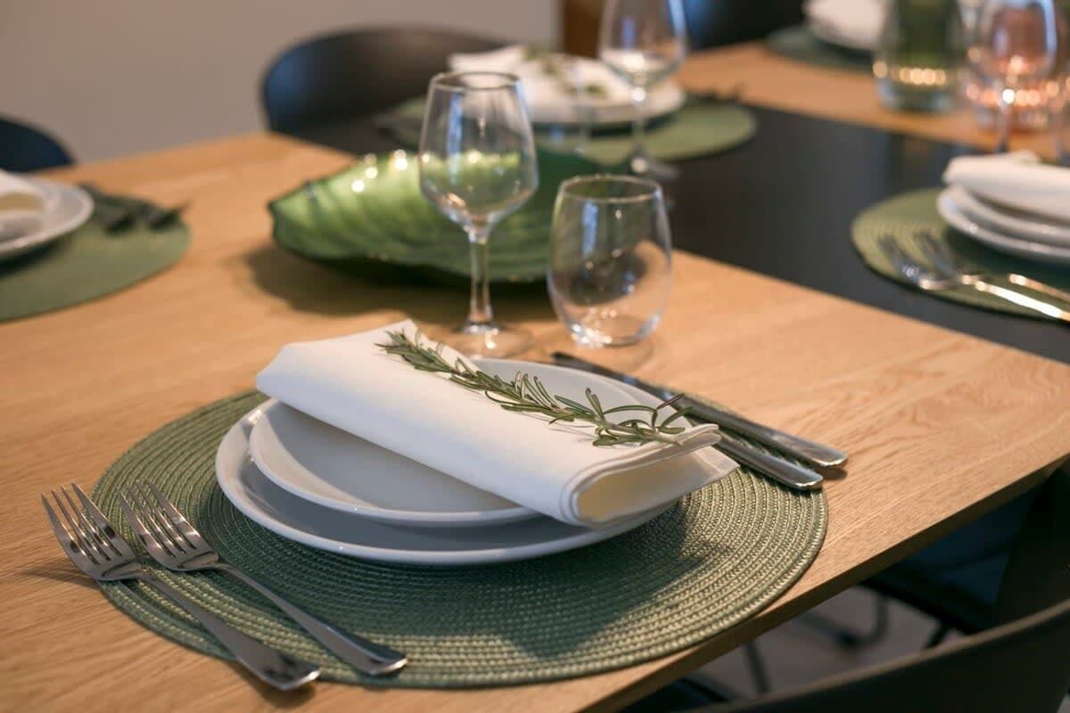 A neatly set dining table with plates, cutlery, and glasses.