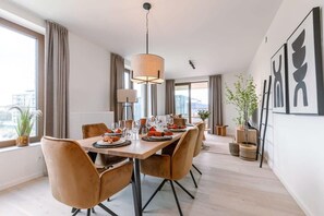 A modern dining area with a wooden table set for four, surrounded by plush chairs. - Coastal escape near beach w/ Terrace (Oostende)