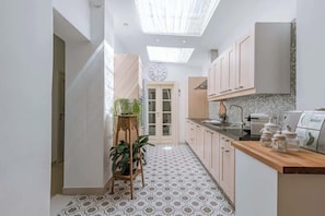 A modern kitchen with a skylight, a clock, and a plant.