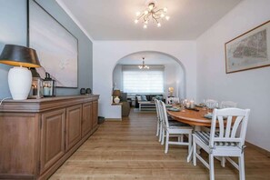 A dining area with a wooden table, white chairs, and a chandelier.