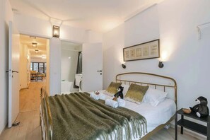 Ein Schlafzimmer mit einem Bett, einem Nachttisch, einem Wandbild und einer Tür zum Badezimmer.