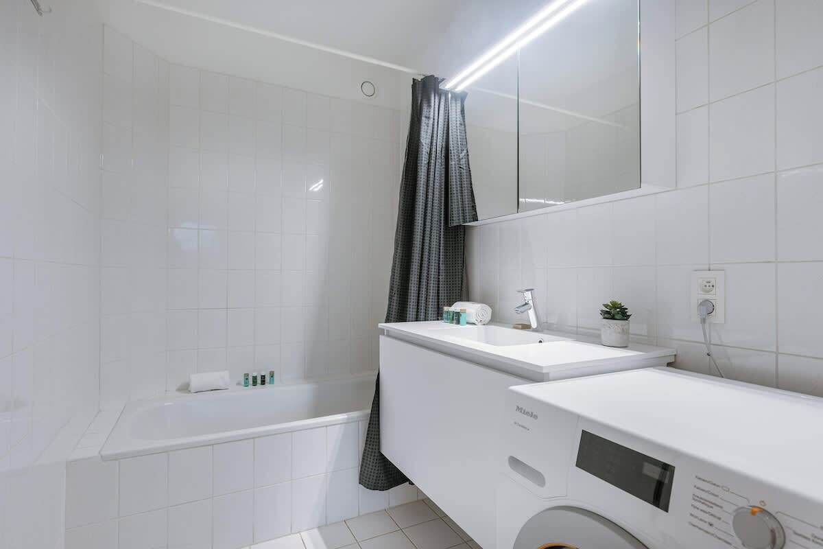 Et moderne badeværelse med badekar, håndvask og spejl.
