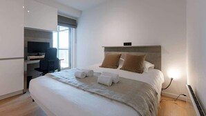 Ein modernes Hotelzimmer mit Bett, Schreibtisch und Fenster.