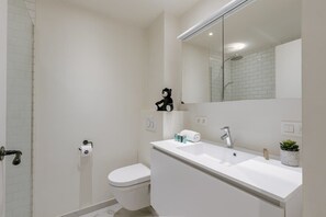 Een moderne badkamer met toilet, wastafel en douche.
