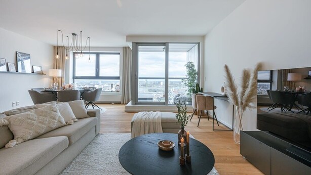 Ein modernes Wohnzimmer mit Sofa, Couchtisch und Essbereich.
