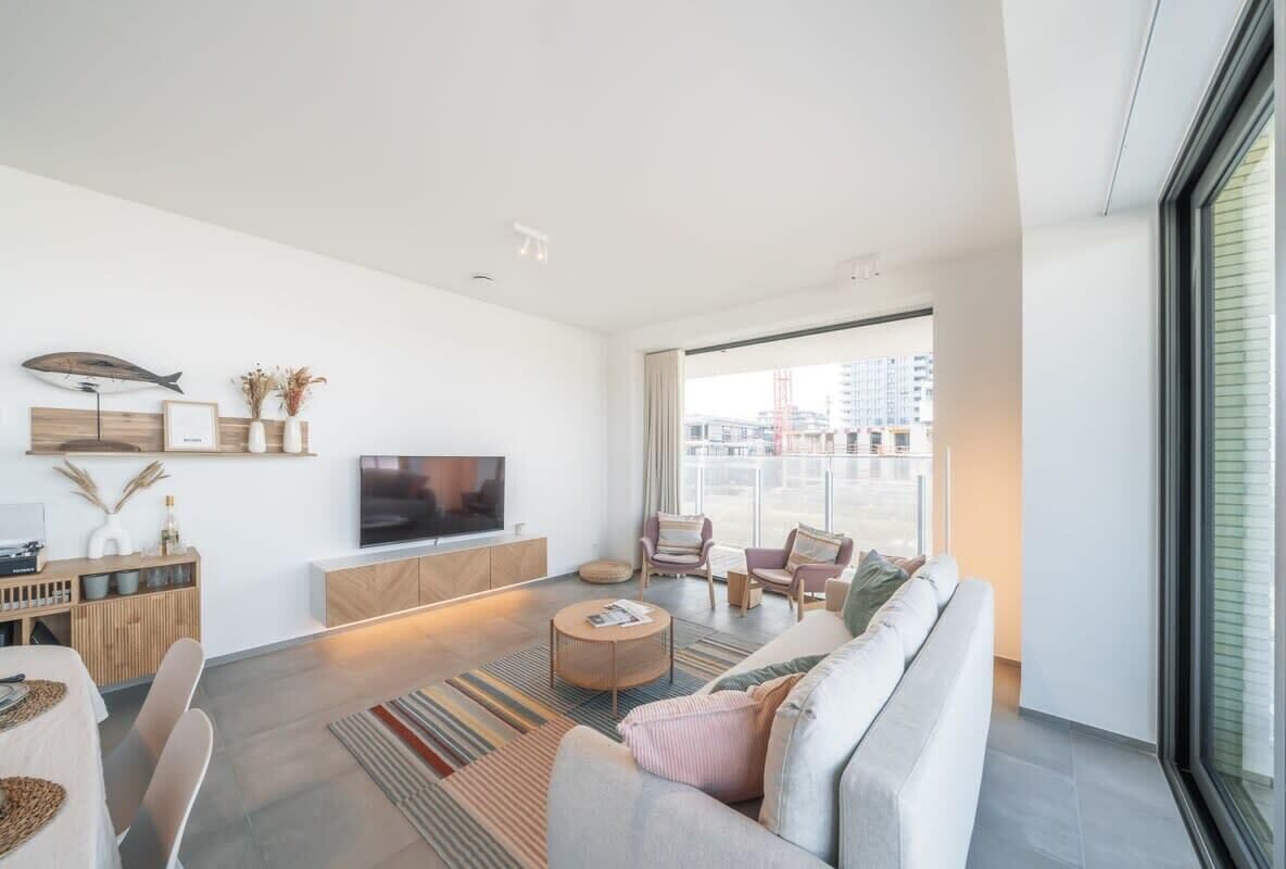 Ein modernes Wohnzimmer mit Sofa, Sesseln, einem Fernseher und einem Essbereich.