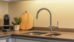 Una cocina moderna con un lavamanos de acero inoxidable, una tabla de cortar de madera y una cafetera.