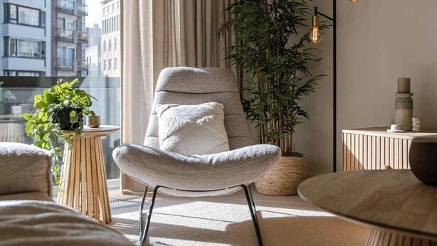 Una sala de estar moderna con un sillón acolchado, una planta en maceta y una lámpara de pie.