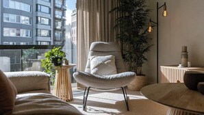 Una sala de estar moderna con un ventanal grande, un sillón cómodo, una planta en maceta y una lámpara de pie.