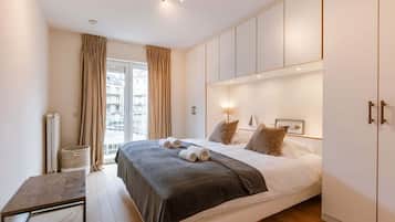 Een slaapkamer met een bed, nachtkastjes, een kledingkast en een raam met gordijnen.