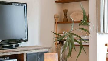 Een woonkamer met een televisie, houten planken, een plant en een kaars op een houten tafel.