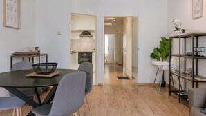 Un apartamento moderno con comedor, cocina y un pasillo que conduce a otra habitación.