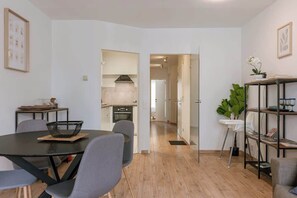 A modern apartment with a dining area, kitchen, and a hallway leading to another room. - Cozy 2BR unit w/ kitchen & TV (Knokke-Heist)