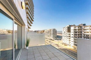Un balcón con vista a un paisaje urbano, que incluye edificios y una carretera.