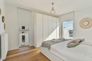 Un dormitorio con cama, radiador, armario y ventana.