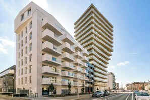 Un edificio moderno de varios pisos con balcones, fachada plana y cielo despejado.