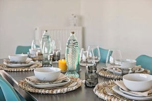 Una mesa de comedor dispuesta con platos, tazones, vasos y una vela.
