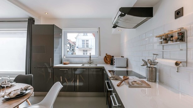 Eine moderne Küche mit Fenster, Edelstahlgeräten und einer weißen Küchenrückwand.
