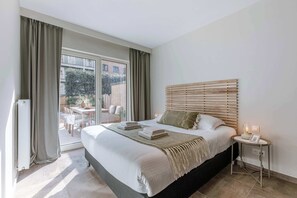 Un dormitorio con una cama grande, una mesita de noche con lámpara y vistas al exterior.