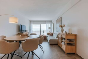 Una sala moderna con comedor, un conjunto de sofás, un aparador de madera y un amplio ventanal con vistas.