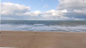 A beach with a wide sandy shore and a view of the ocean under a partly cloudy sky. - Casiola waterfront apt - garage & sea views (Oostende)