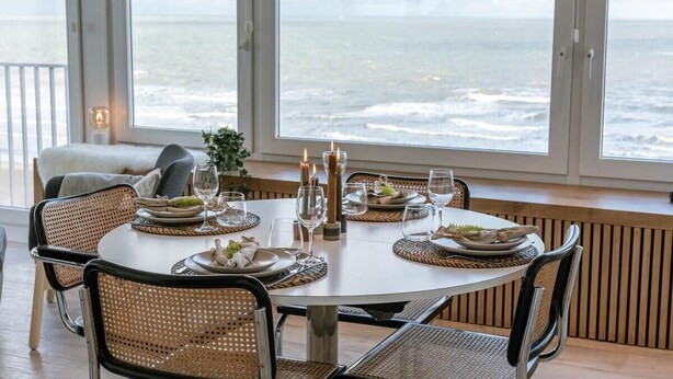 A round dining table set for four with candles, plates, and glasses. - Casiola waterfront apt - garage & sea views (Oostende)