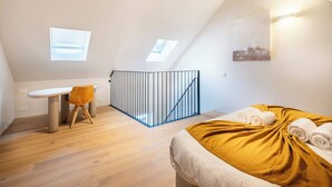 A modern bedroom with a bed, a desk, and a chair. - Light-filled duplex w/ workspace & TV (Gent)