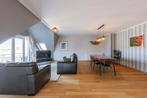 Una sala moderna con un sofá, una mesa de comedor con sillas, un televisor y una lámpara en el techo.
