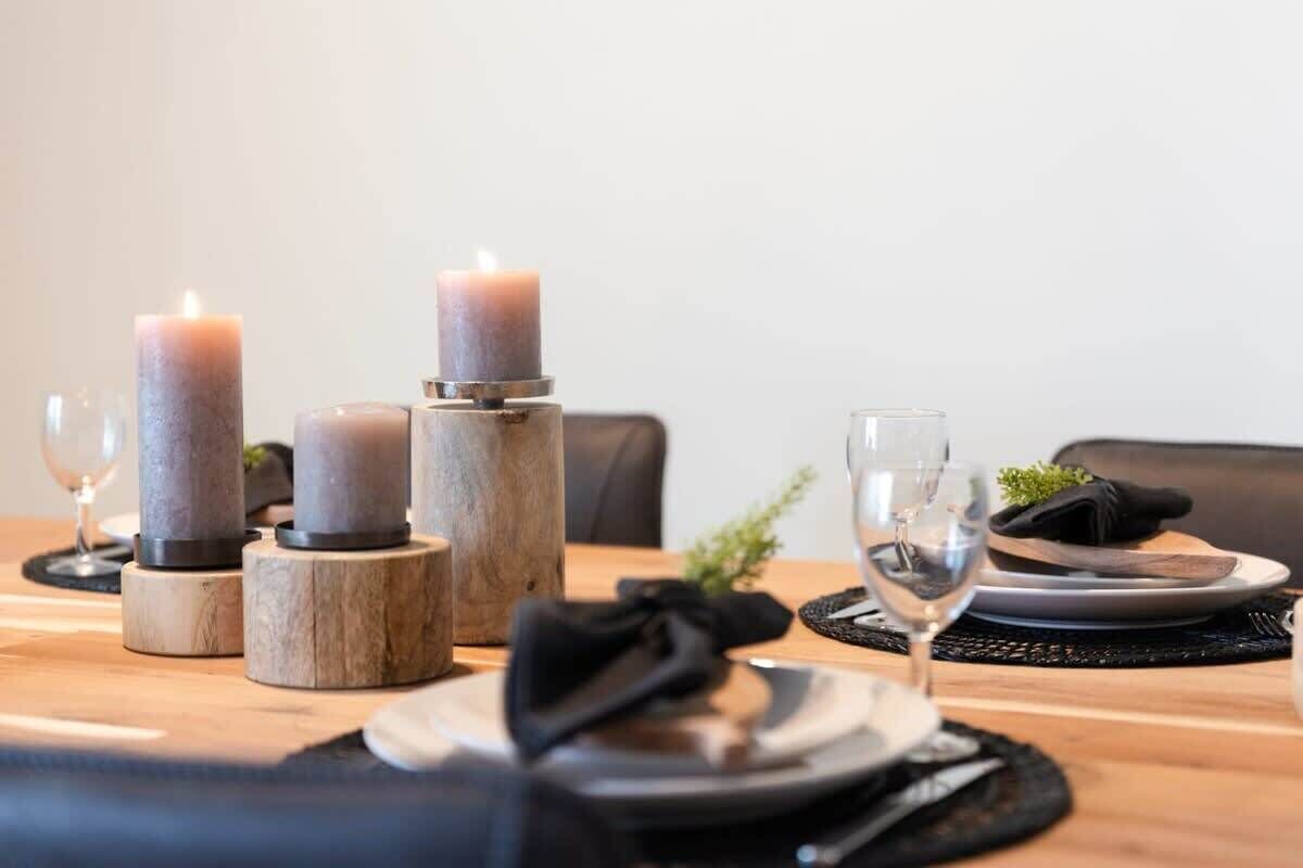 A dining table with candles, plates, and cutlery.