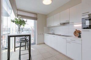 Eine moderne Küche mit weißen Schränken, einer Edelstahl-Spüle und einem großen Fenster mit Blick auf die Stadt.
