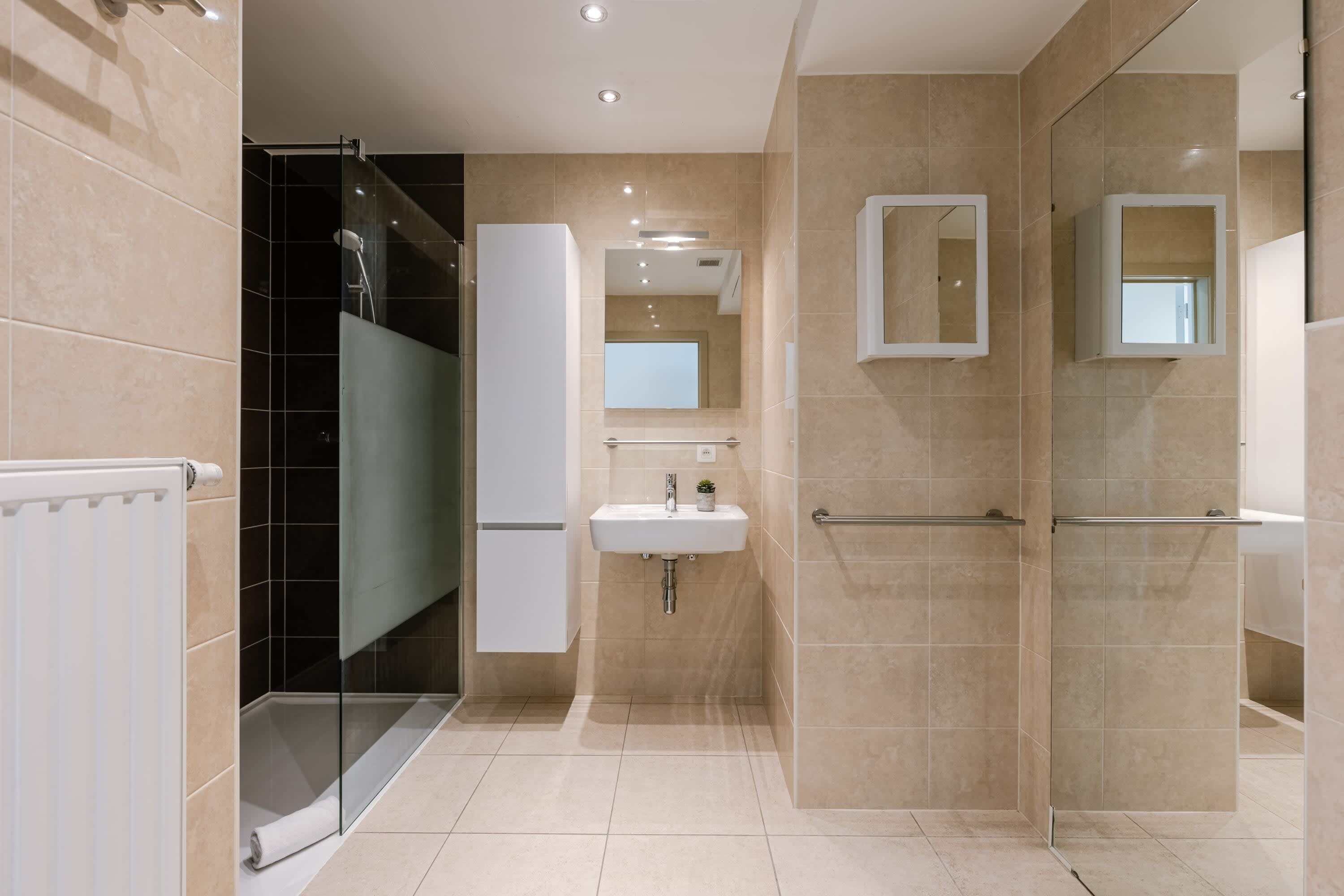 Une salle de bain moderne avec une douche à parois de verre, un lavabo blanc et un miroir.