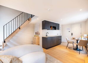 Eine moderne Wohnung mit Treppe, Küche, Essbereich und Wohnzimmer.