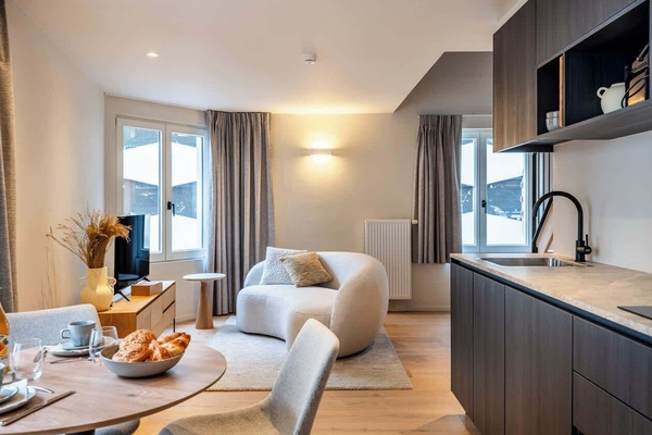 Modern living area with a curved sofa and integrated kitchen space.
