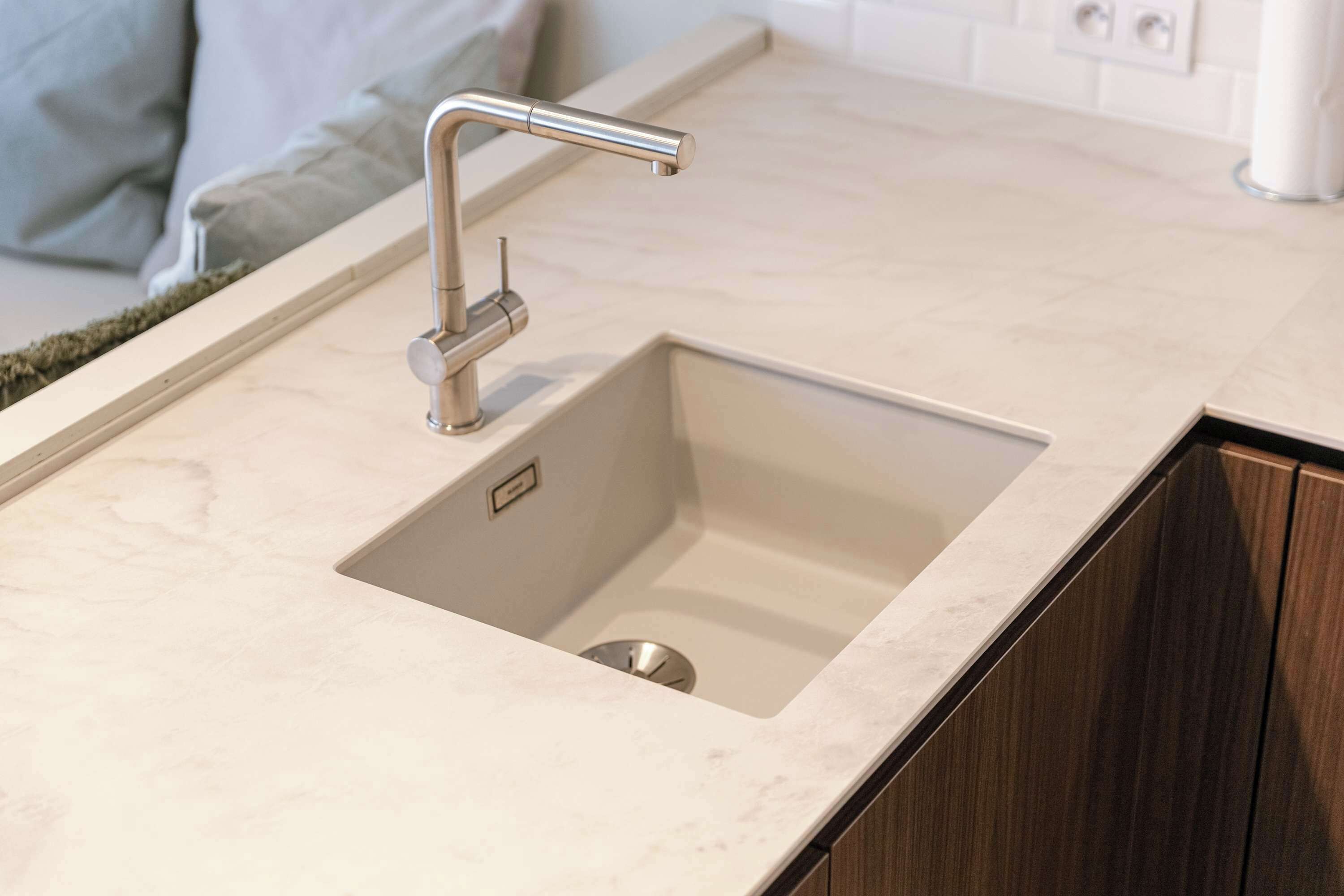 Una cocina moderna con un lavamanos de acero inoxidable, encimera de mármol y armarios de madera.
