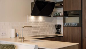 A modern kitchen with a built-in oven, a stainless steel range hood, and a white tiled backsplash. - Coastal retreat near Belgian coast (Knokke-Heist)