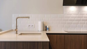 A modern kitchen with a stainless steel faucet, white subway tiles backsplash, and wooden cabinets. - Coastal retreat near Belgian coast (Knokke-Heist)