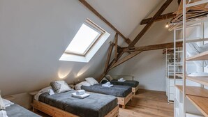 A loft bedroom with two beds, a skylight, wooden beams, and built-in shelving. - Historic apartment w/ kitchen (Gent)