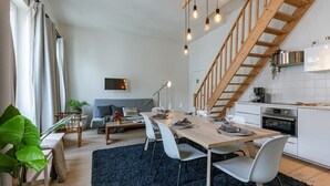 A modern kitchen with white cabinets, a wooden staircase, and a dining area with a table and chairs. - Historic apartment w/ kitchen (Gent)