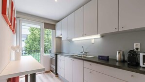 Een moderne keuken met een groot raam, een ingebouwde oven en een koffieapparaat.