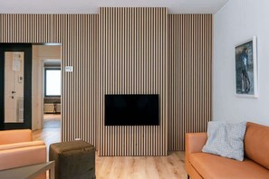 Un salon moderne avec un téléviseur à écran plat fixé sur un mur composé de lattes de bois, un canapé et une table basse.