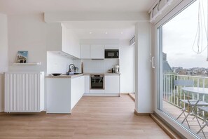Een moderne keuken met witte kastjes, een inbouwoven en een magnetron.
