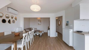 Een moderne keuken met witte kastjes, een houten eettafel en een centraal keukenblok.
