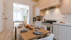 Eine moderne Küche mit Holzschränken, einem Gasherd und einem Essbereich mit einem Holztisch, gedeckt für vier Personen.
